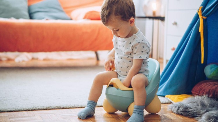 Ilustrasi Cara Melepas Popok untuk Ajarkan Toilet Training Baby boy in boots sitting on potty.