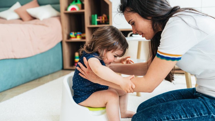 Ilustrasi Cara Melepas Popok untuk Ajarkan Toilet Training Young Mother training her toddler girl to use the potty