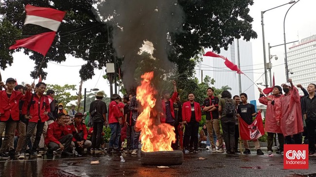 Massa aksi dari Gerakan Mahasiswa Nasional Indonesia (GMNI) membakar ban saat berunjuk rasa di kawasan patung kuda, Jakarta Pusat.