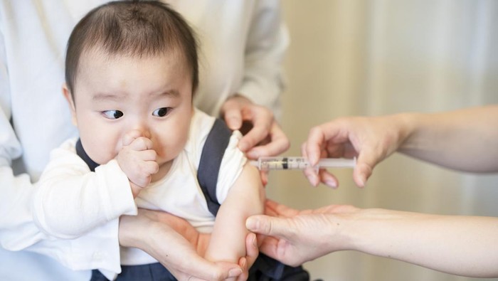 A baby who is vaccinated while being held by her mother