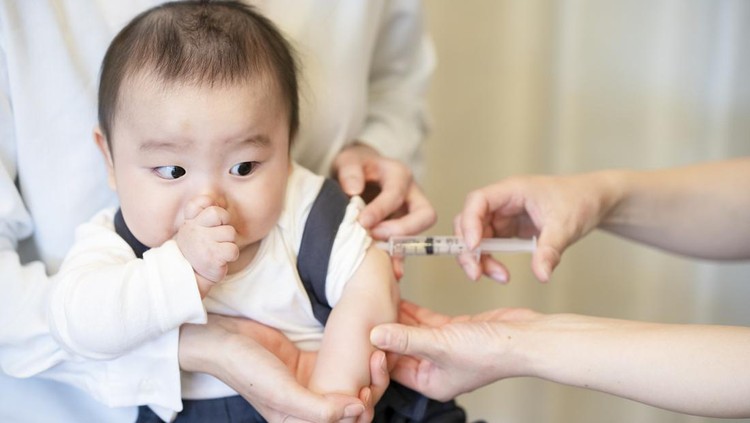 A baby who is vaccinated while being held by her mother