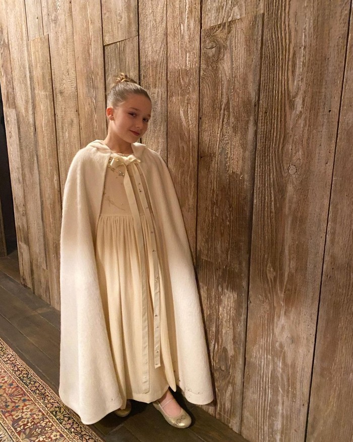 Untuk acara pembaptisannya di gereja, ia terlihat lebih rapi dan anggun. Harper memakai maxi dress krem berhias manik-manik emas pada bodice. Gaun indah itu dilapisi cape panjang berwarna senada. Foto: instagram.com/victoriabeckham