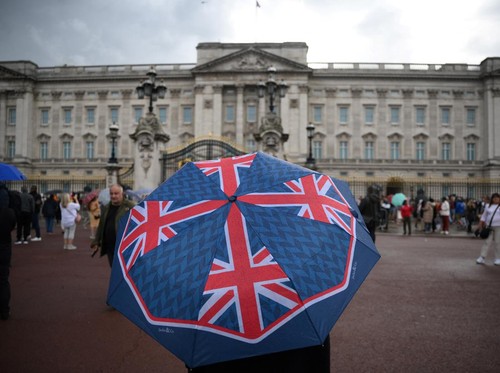 A person with an umbrella picturing the British national flag stands guard in front of Buckingham palace, central London, on September 8, 2022. - Fears grew on September 8, 2022 for Queen Elizabeth II after Buckingham Palace said her doctors were "co