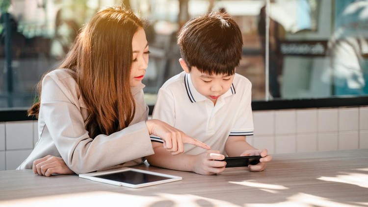 Business woman working online in cafe with kid. Asian family lifestyle with mobile phone and digital tablet.
