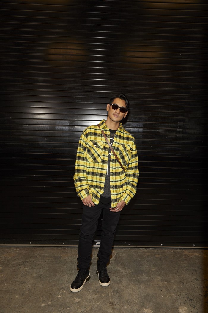 Afgan memilih kemeja oversized flannel dalam warna yang senada dengan Isyana. Ia juga memadukannay dengan tas Coach Bandit. Foto: Coach