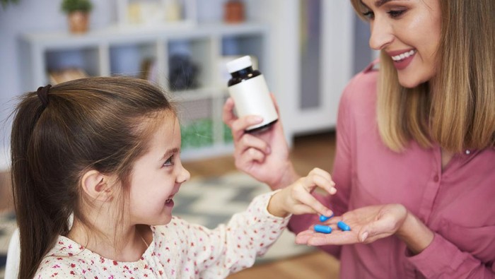 Young mum giving her little daughter the medicine