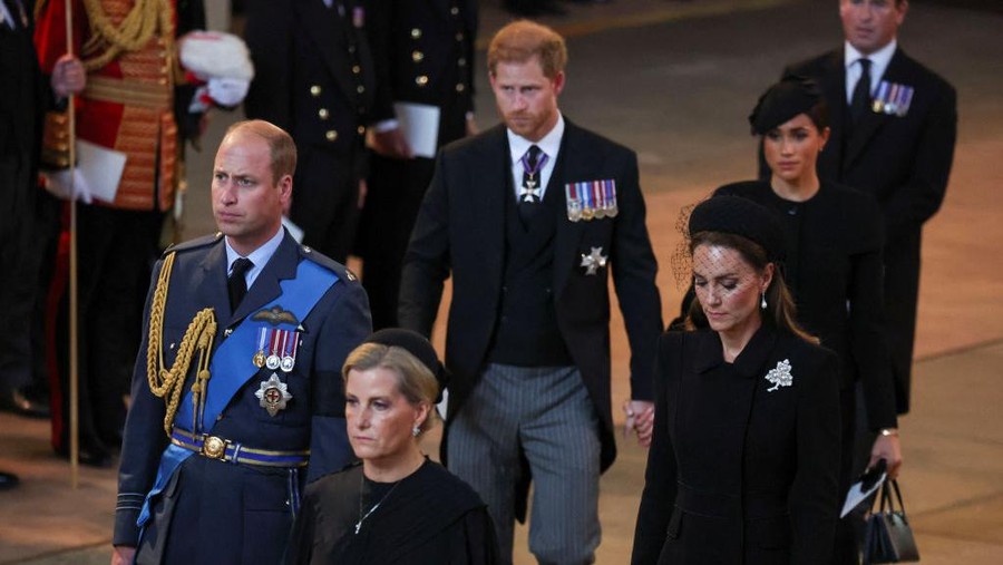 LONDON, ENGLAND - SEPTEMBER 14: Prince Harry and Meghan, Duchess of Sussex walk as procession with the coffin of Britain's Queen Elizabeth arrives at Westminster Hall from Buckingham Palace for her lying in state on September 14, 2022 in London, United Kingdom. Queen Elizabeth II's coffin is taken in procession on a Gun Carriage of The King's Troop Royal Horse Artillery from Buckingham Palace to Westminster Hall where she will lay in state until the early morning of her funeral. Queen Elizabeth II died at Balmoral Castle in Scotland on September 8, 2022, and is succeeded by her eldest son, King Charles III. (Photo by Phil Noble - WPA Pool/Getty Images)