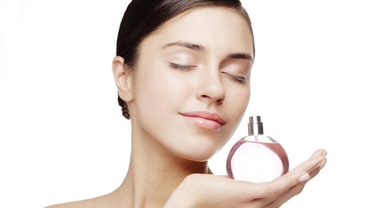 young female smelling a bottle of perfume