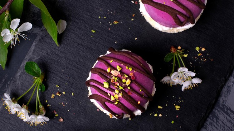 Bilberry mousse cakes semisphere-shaped and topped with chocolate and pistachio nuts. Top view