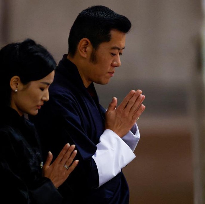 <p>Sesampainya di sana, Raja Bhutan dan istrinya turut berdoa di kesempatan itu. Mereka berdoa sambil memejamkan mata dengan khusyuk di depan peti jenazah Ratu Elizabeth II. (Foto: SARAH MEYSSONNIER, John Sibley-WPA Pool/Getty Images)</p>
