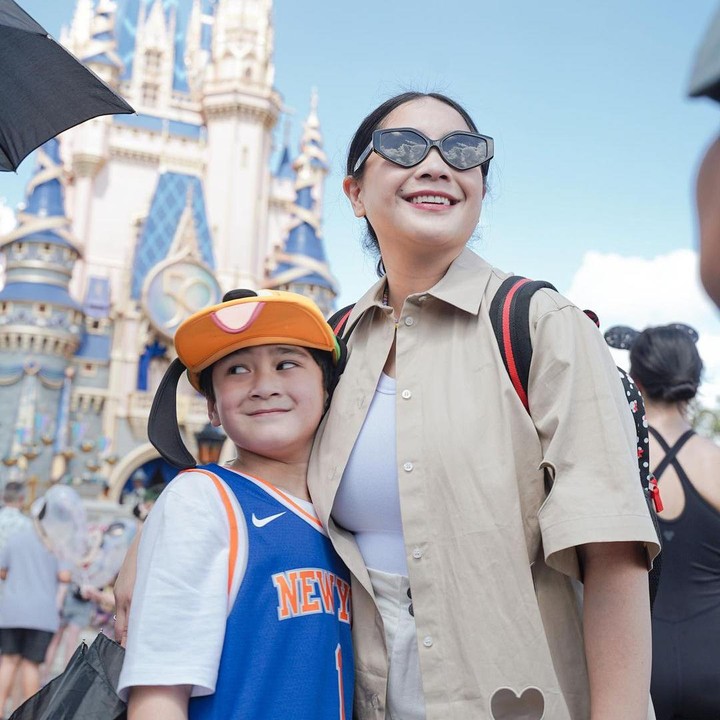 <p>Nagita Slavina yang tampil kece mengenakan <em>sunglasses</em> juga mengajak si sulung berpose di depan Disney Castle, nih. (Foto: Instagram @raffinagita1717)</p>