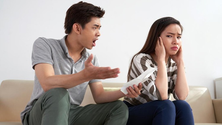 Family quarrel: angry Asian man shouting at his young wife after received telephone bills, she closing her eyes with hands