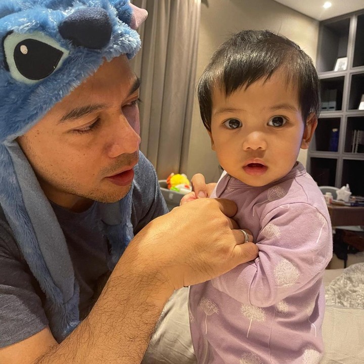 <p>Selain sering bermain dengan ketiga kakaknya, Nakeya juga terlihat anteng ditemani Ayahnya. Ayah Baldy terlihat memakai topi karakter Stitch saat bermain dengan Nakeya. (Foto: Instagram/riafinola)</p>
