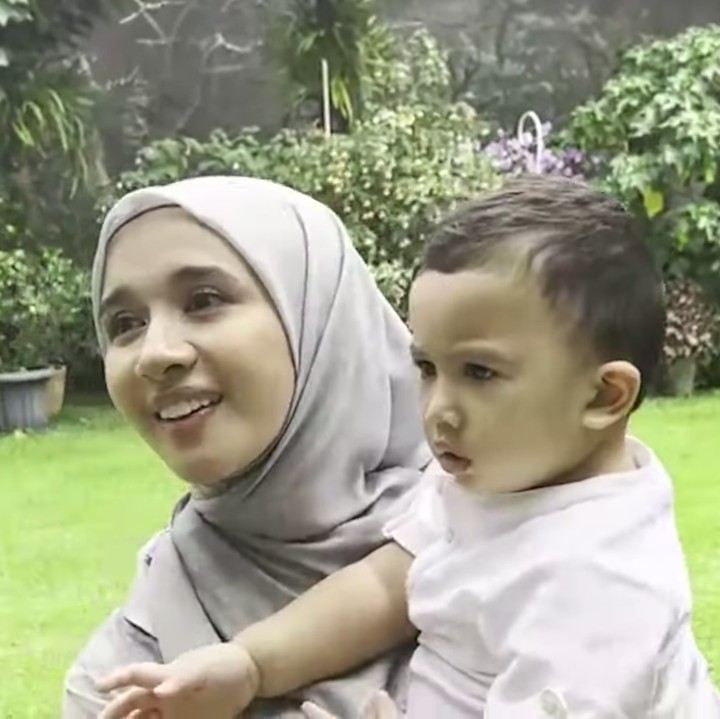 <p>Meski terlihat lelah dan keberatan dengan bobot Ukkasya, Bella tetap merasa senang bertemu dengan bayi yang lahir pada 30 Maret 2021 ini. (Foto: YouTube The Sungkars)</p>