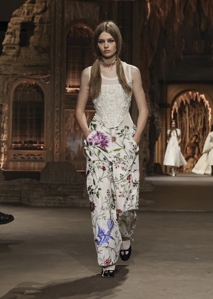 Celana cargo yang berkesan boyish dibuat lebih feminin lewat motif bunga oleh Dior. Trik lain yang bisa ditiru adalah padanan celana ini bersama corset top.Foto: Courtesy of Dior