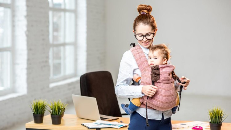 Portrait of a businesswoman standing with her baby son at the white office interior during the break