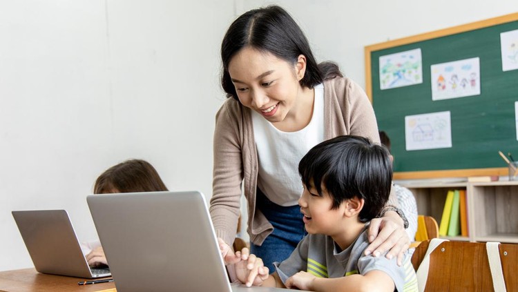 An Asian female teacher teaches primary school students to use computers and tablets to search for knowledge and information through the Internet. Classroom diversity students. Back to school concept