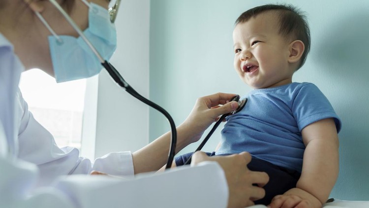 Asian female Pediatrician doctor examining little cute smiling Baby boy with stethoscope in medical room at hospital.