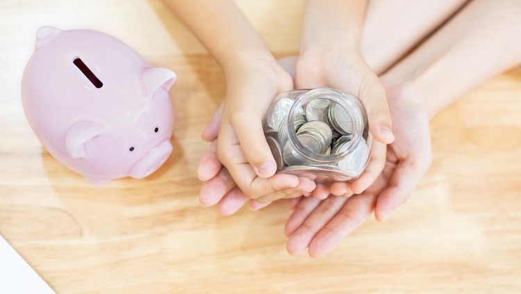 close up of Girl and her mother hold cash and money bottle and there is a pink piggy bank on table