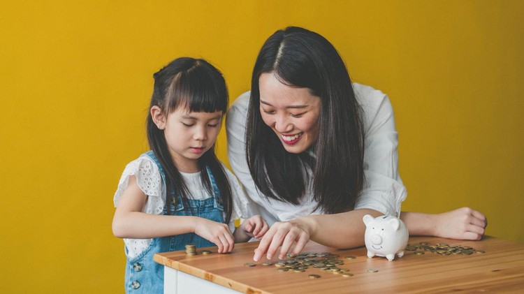 Young Asian Mother and her daughter count coins from piggy bank.