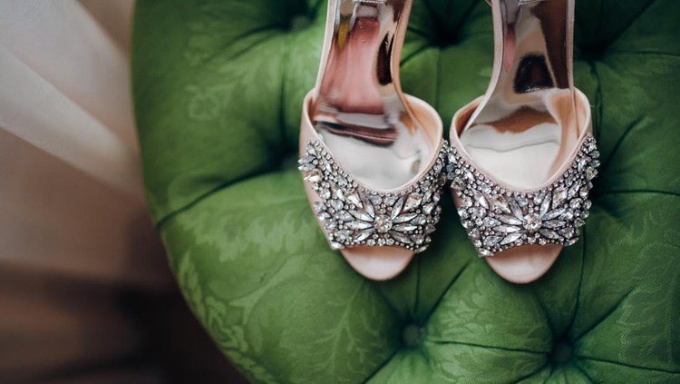 designer wedding shoes decorated with stones stand on a green soft sofa