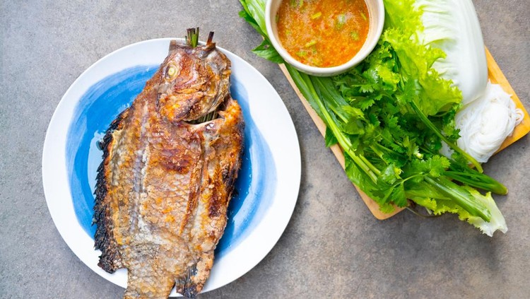 Tilapia grilled with salt in Thai style food eating with seafood sauce and fresh vegetable is a healthy Thai food