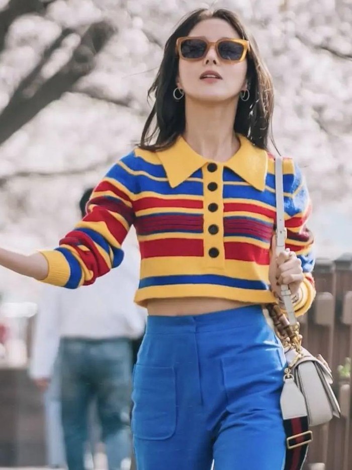 Di masa kini, Kim Yu Ri menjadi seorang pengacara yang ingin membuka kafe. Nah, saat melihat gedung untuk kafe, ia pakai atasan rajut warna-warni dari Cider yang dipadu dengan celana jeans./ Foto: instagram.com/leeseyoungstyle