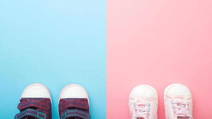 Two pairs of sport shoes for little boys and girls. Pastel blue pink background. Baby footwear. Empty place for text. Top down view.