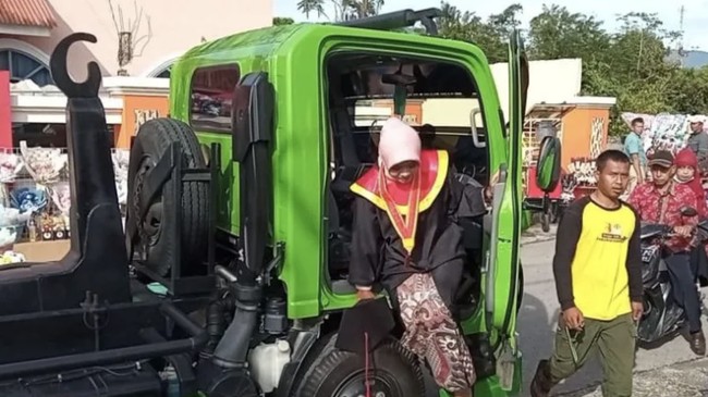 Mitra Yoriskia, pekerja DLH Solok mengendarai truk sampah menuju seremoni wisudanya di Universitas Mahaputra Muhammad Yamin.
