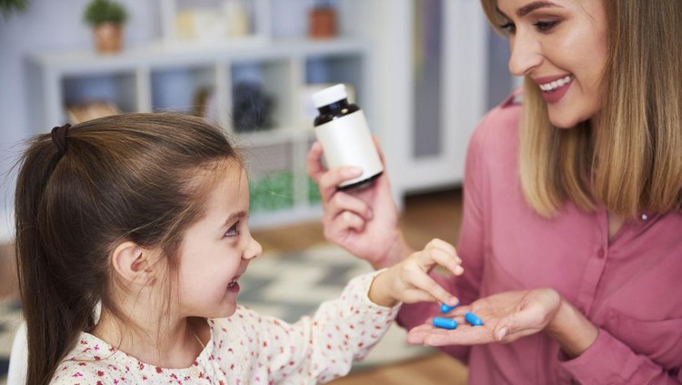 Ilustrasi Vitamin Daya Tahan Tubuh Anak Young mum giving her little daughter the medicine