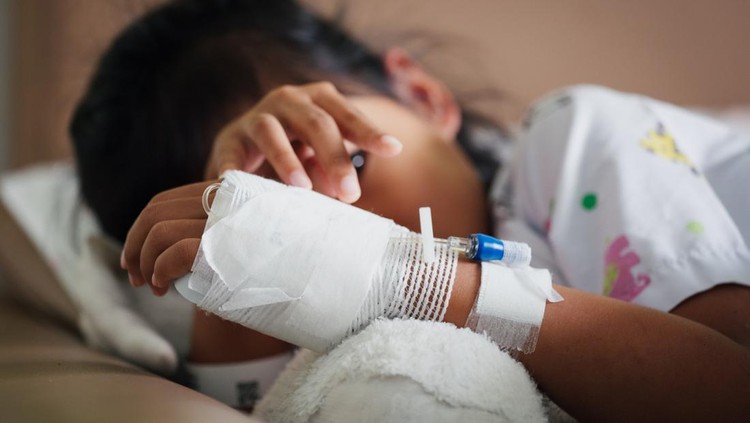Sick kid feeling unwell lying down and hugging her doll in the bed while stay in private patient rooms in the hospital. Healthcare and lifestyle concept.