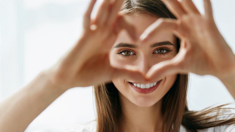 943085232 Healthy Eyes And Vision. Portrait Of Beautiful Happy Woman Holding Heart Shaped Hands Near Eyes. Closeup Of Smiling Girl With Healthy Skin Showing Love Sign. Eyecare. High Resolution Image