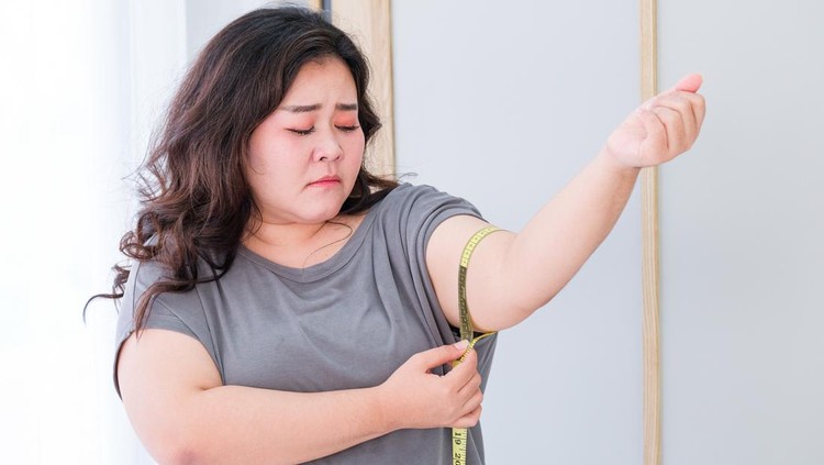 Asian fat women are sad because of the increase in size after checking with a tape measure.