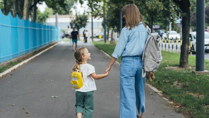 Anonymous Mother walking together with her daughter, holding her hand