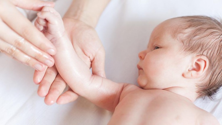 Mother makes massage for happy baby, apply oil on the hand, with white background