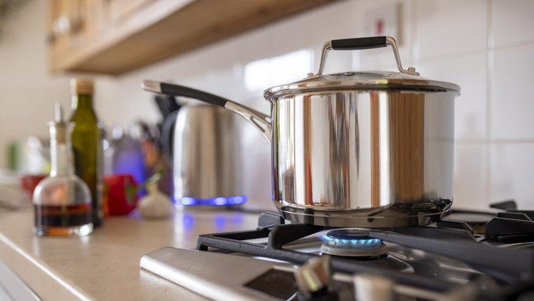 1369588167 Close-up side-view shot of a cooking pot on a gas stove. Using a single ring to save extra cost of using gas as current energy prices increase.