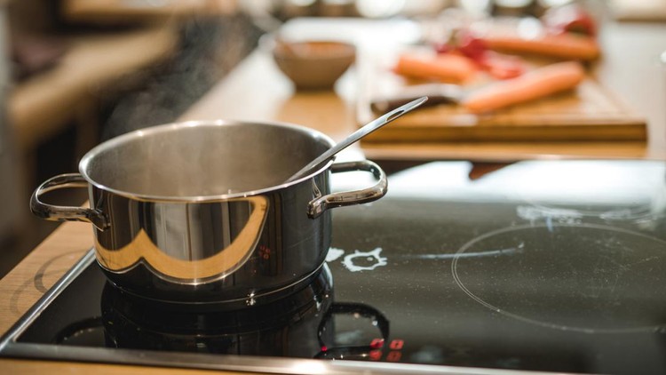 Saucepan with steam on a stove in the kitchen.