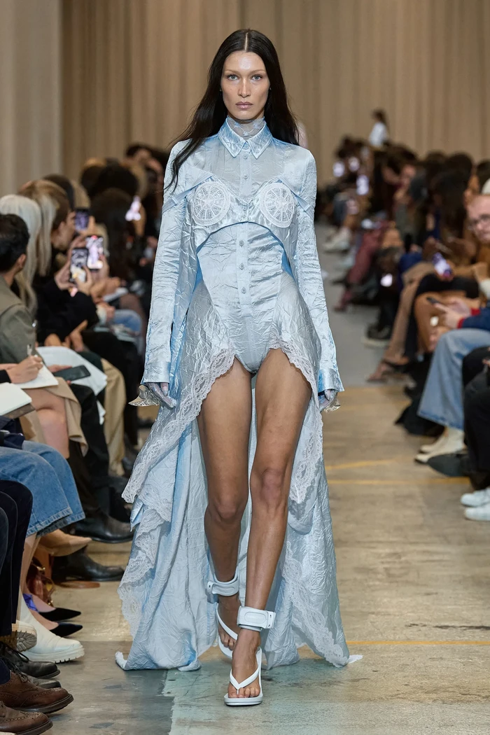 Garis desain feminin yang sensual juga dihadirkan Tisci lewat padanan kemeja dan gaun lace biru yang dikenakan Bella Hadid. Foto: Courtesy of Burberry