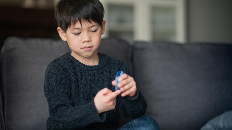 Ilustrasi Anak Diabetes Militus Tipe 1 A boy is sitting in the living room. He is checking his blood sugar level because he is diabetic.
