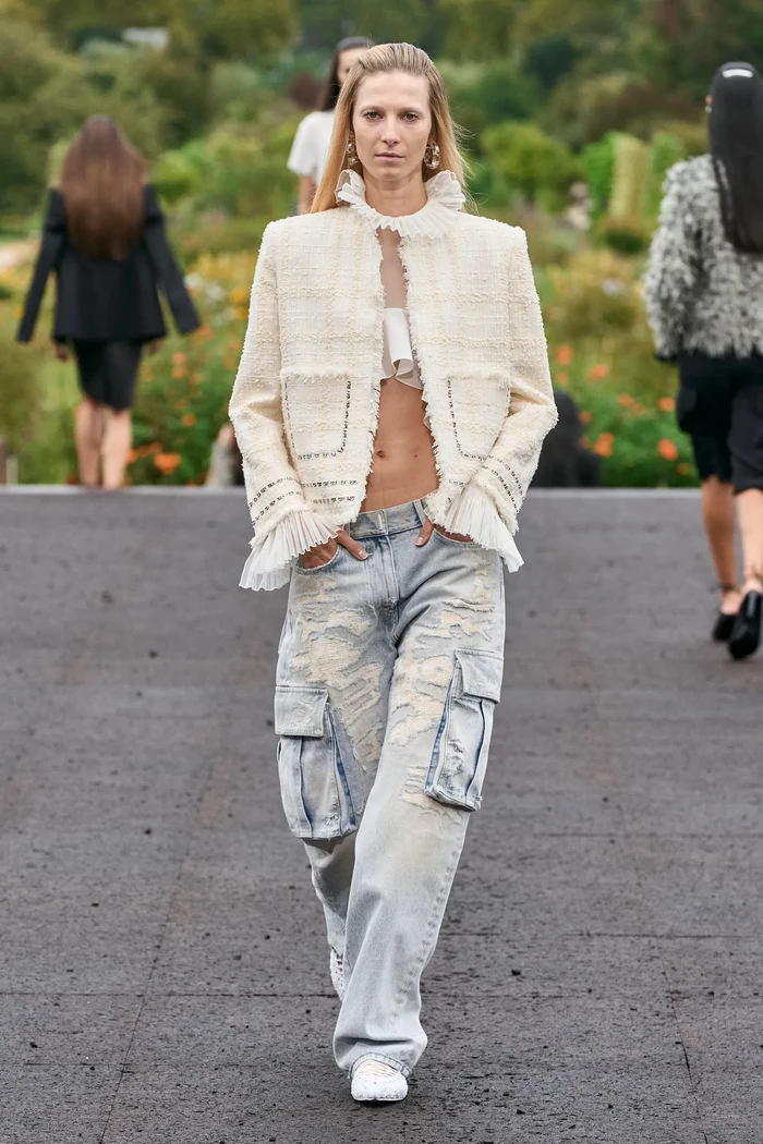 Gaya kasual feminin diusung Givenchy lewat kombinasi denim cargo pants bersama crop top aksen ruffles dan jaket tweed. Foto: Alessandro Lucioni / Gorunway.com/Vogue