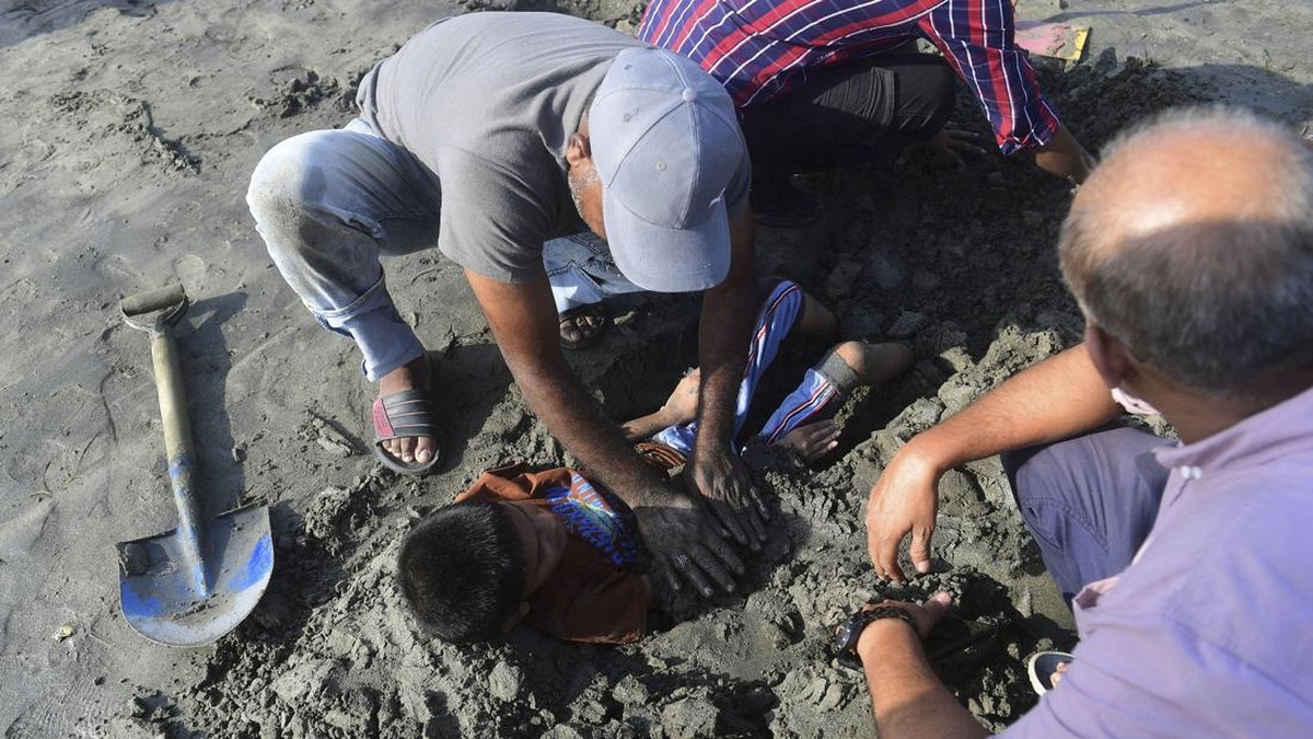 FOTO: Anak-anak Pakistan 'Dikubur' saat Gerhana, Dipercaya Berkhasiat