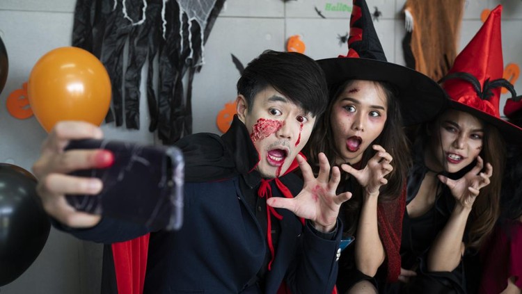 Young Asian people, a group of three persons, in scary costumes selfie their own photo. Group of friends having fun at a party in a nightclub to celebrate Halloween festival.
