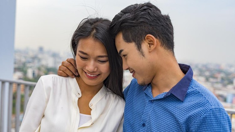 802318350 Young Asian couple hugging on a rooftop overlooking Bangkok