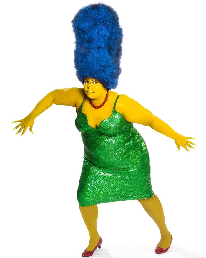 Lizzo mengecat seluruh tubuhnya menjadi kuning demi menjadi Marge Simpson. Rambut biru menjulang, gaun hijau, dan kalung merah yang identik dengan karakter serial The Simpson itu lengkap dipakai sang penyanyi. Foto: instagram.com/lizzobeeating