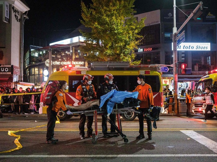 TOPSHOT - This picture taken on October 30, 2022 shows emergency workers standing beside a stretcher with the body of a victim of a Halloween stampede in the district of Itaewon in Seoul. - More than 150 people have been killed in a stampede at a Halloween event in Seoul, officials said on October 30, with South Korea's president vowing a thorough investigation into one of the country's worst-ever disasters. (Photo by Albert RETIEF / AFP) (Photo by ALBERT RETIEF/AFP via Getty Images)