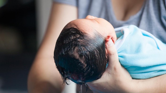 Cute asian newborn baby girl take a bath. Mom cleaning her baby hair.