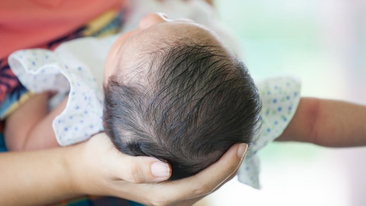 Ilustrasi Rekomendasi Minyak Rambut Bayi Mother holding head of her newborn baby girl in hand with love