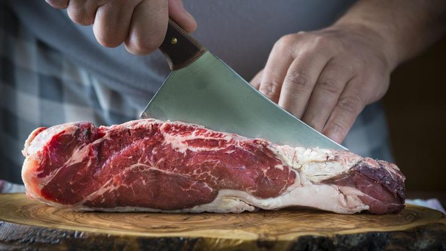 Ilustrasi hewan sembelihan Butcher cutting a piece of meat on a board with a cleaver