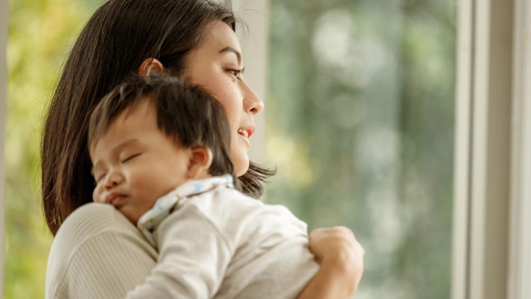 1285879823 Beautiful young Asian mother holding and hugging her newborn baby in room.single mom motherhood stressful concept.