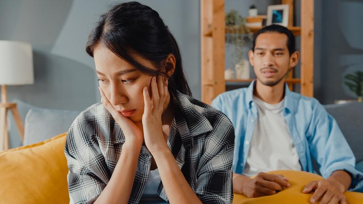 Upset asian couple wife sit on couch listen to furious husband yelling feel unhappy talk negative to her. Couple have fight or disagreement at home, Couple problem, family married toxic relationship.